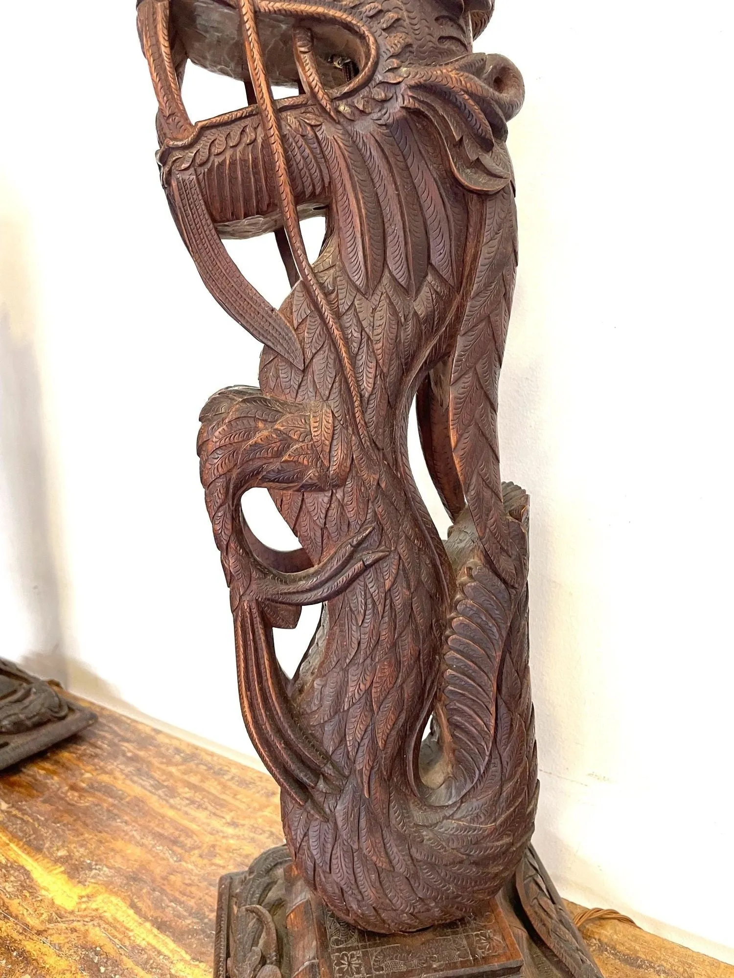 A pair of intricately carved Burmese dragon lamps each mounted on carved wooden base.
