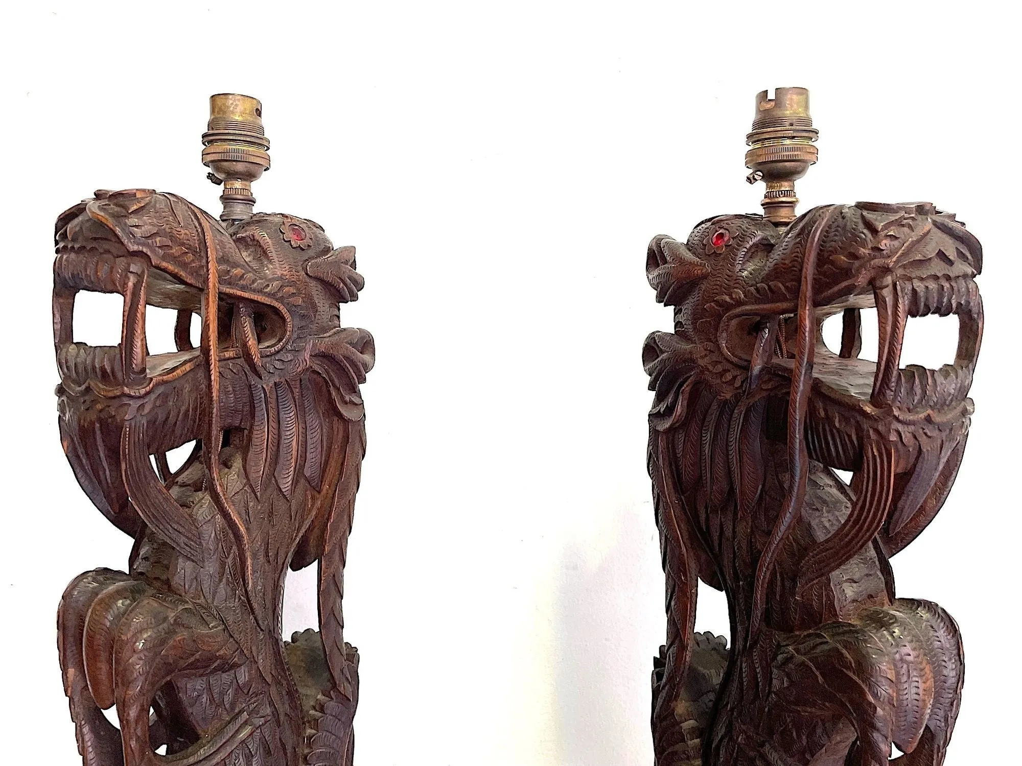 A pair of intricately carved Burmese dragon lamps each mounted on carved wooden base.