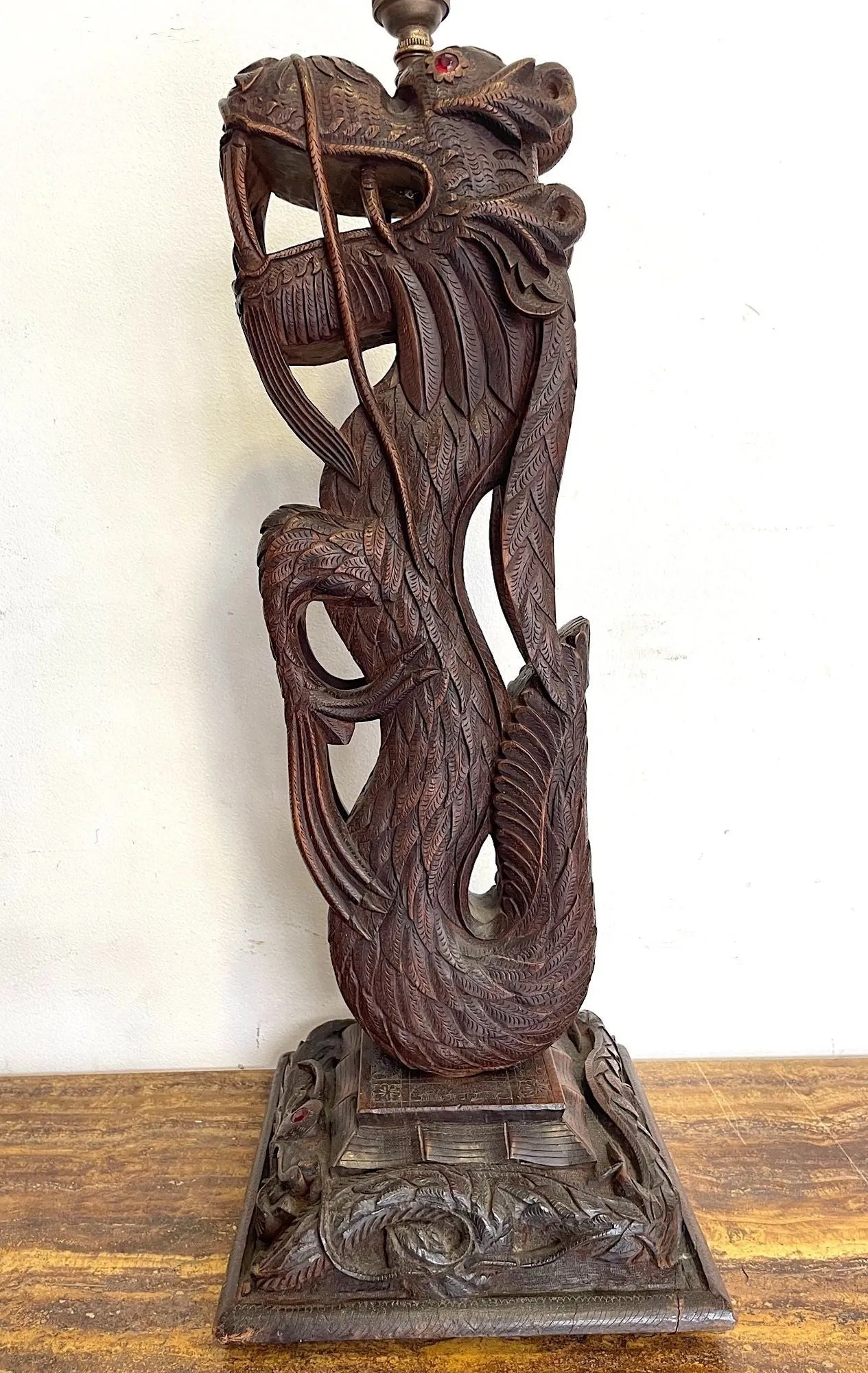 A pair of intricately carved Burmese dragon lamps each mounted on carved wooden base.