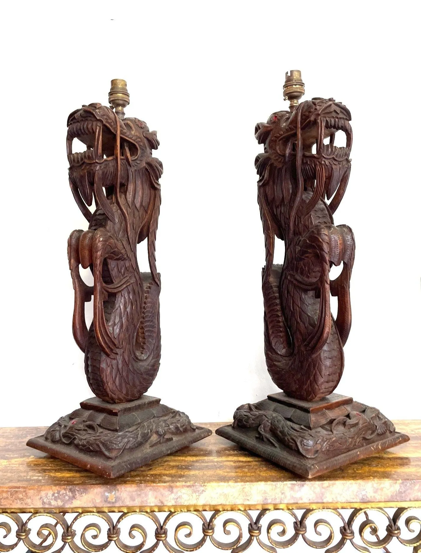 A pair of intricately carved Burmese dragon lamps each mounted on carved wooden base.