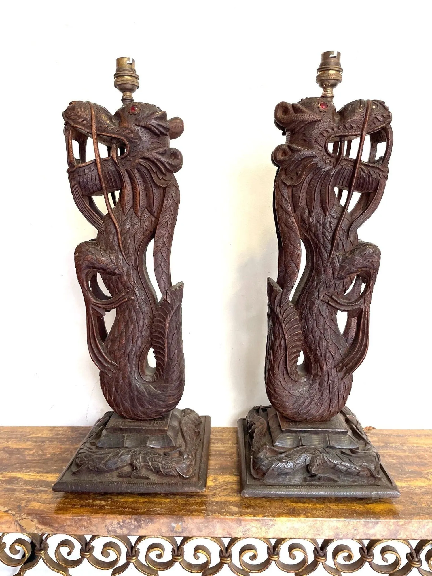 A pair of intricately carved Burmese dragon lamps each mounted on carved wooden base.