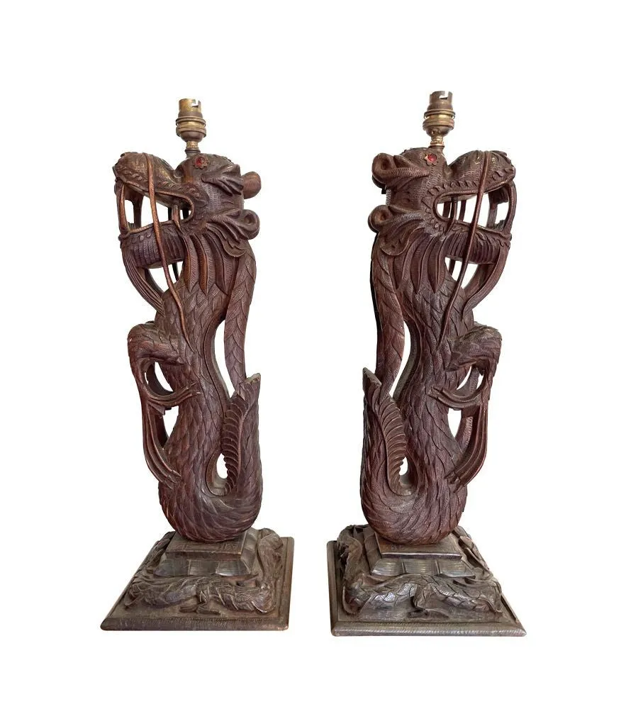 A pair of intricately carved Burmese dragon lamps each mounted on carved wooden base.