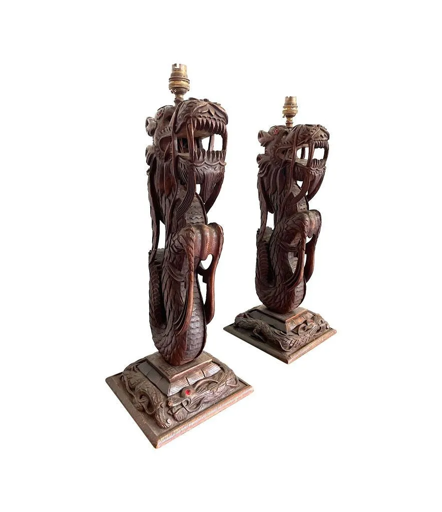 A pair of intricately carved Burmese dragon lamps each mounted on carved wooden base.