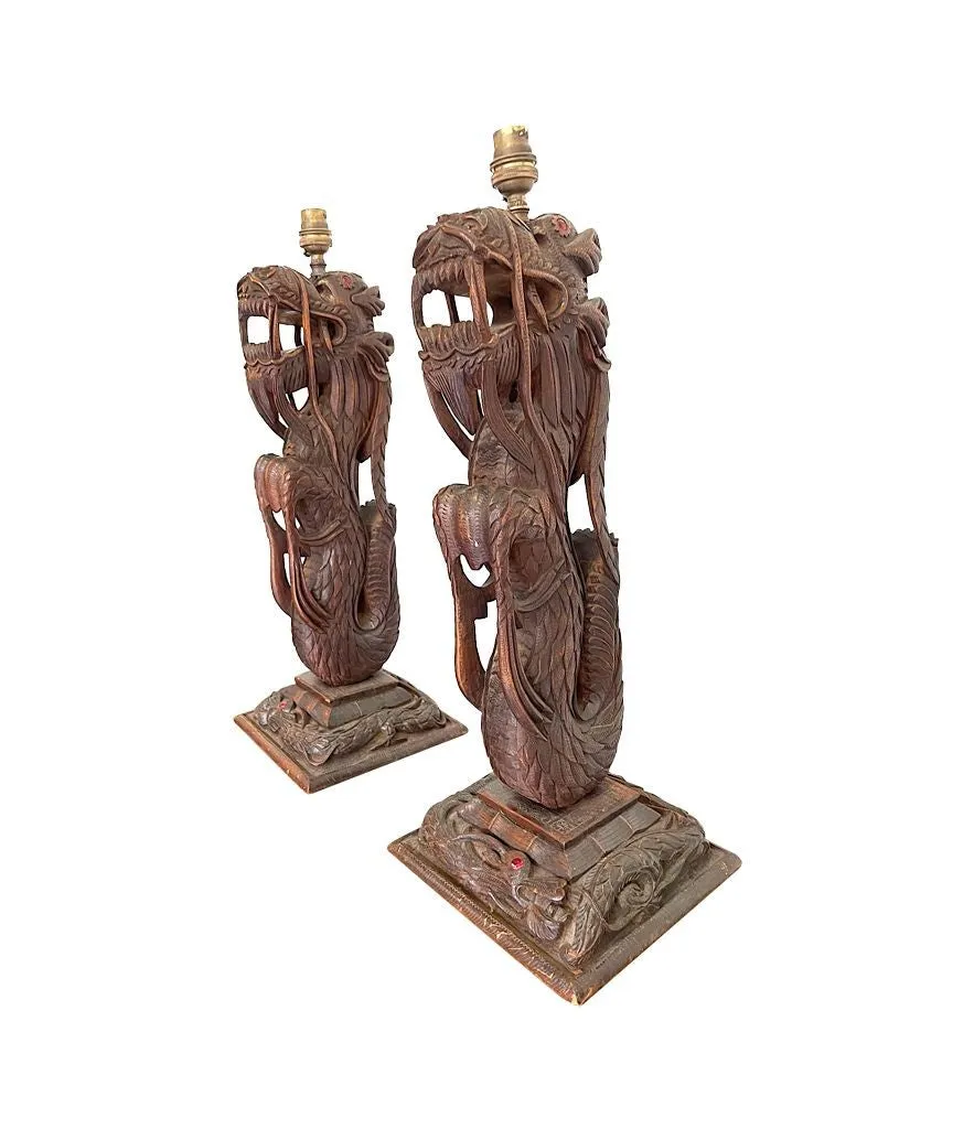 A pair of intricately carved Burmese dragon lamps each mounted on carved wooden base.