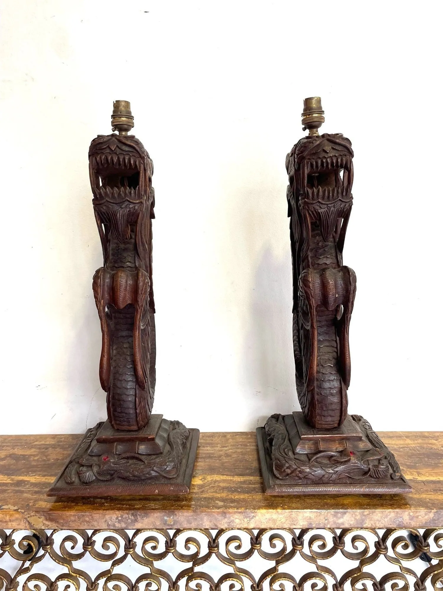 A pair of intricately carved Burmese dragon lamps each mounted on carved wooden base.